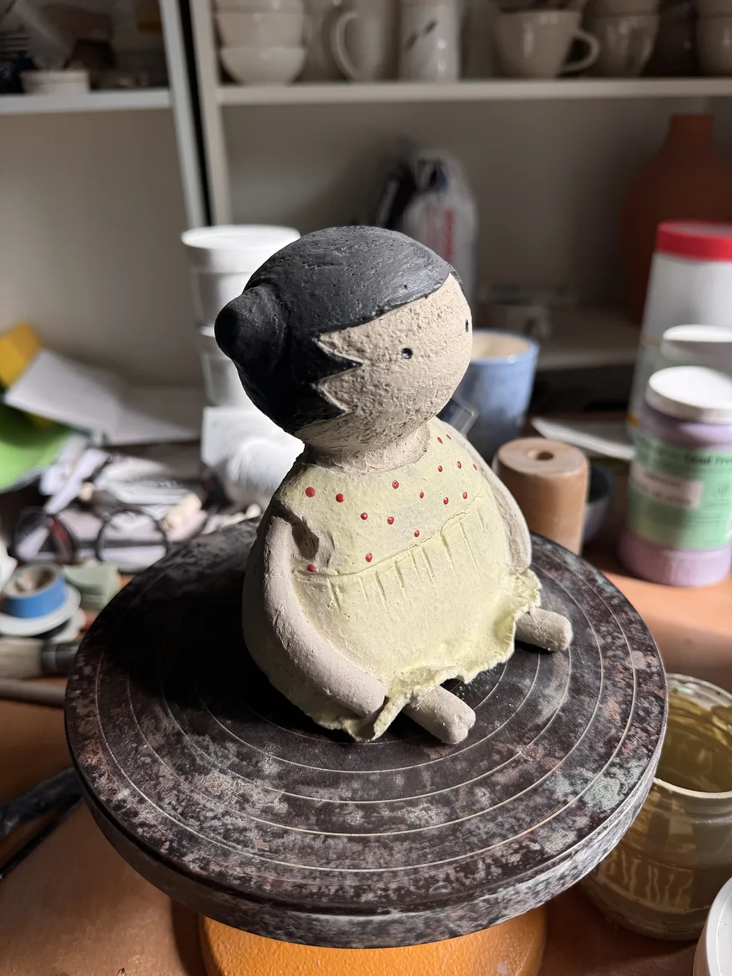 Puppe mit gelbem Kleid und roten Punkten auf dem Drehteller