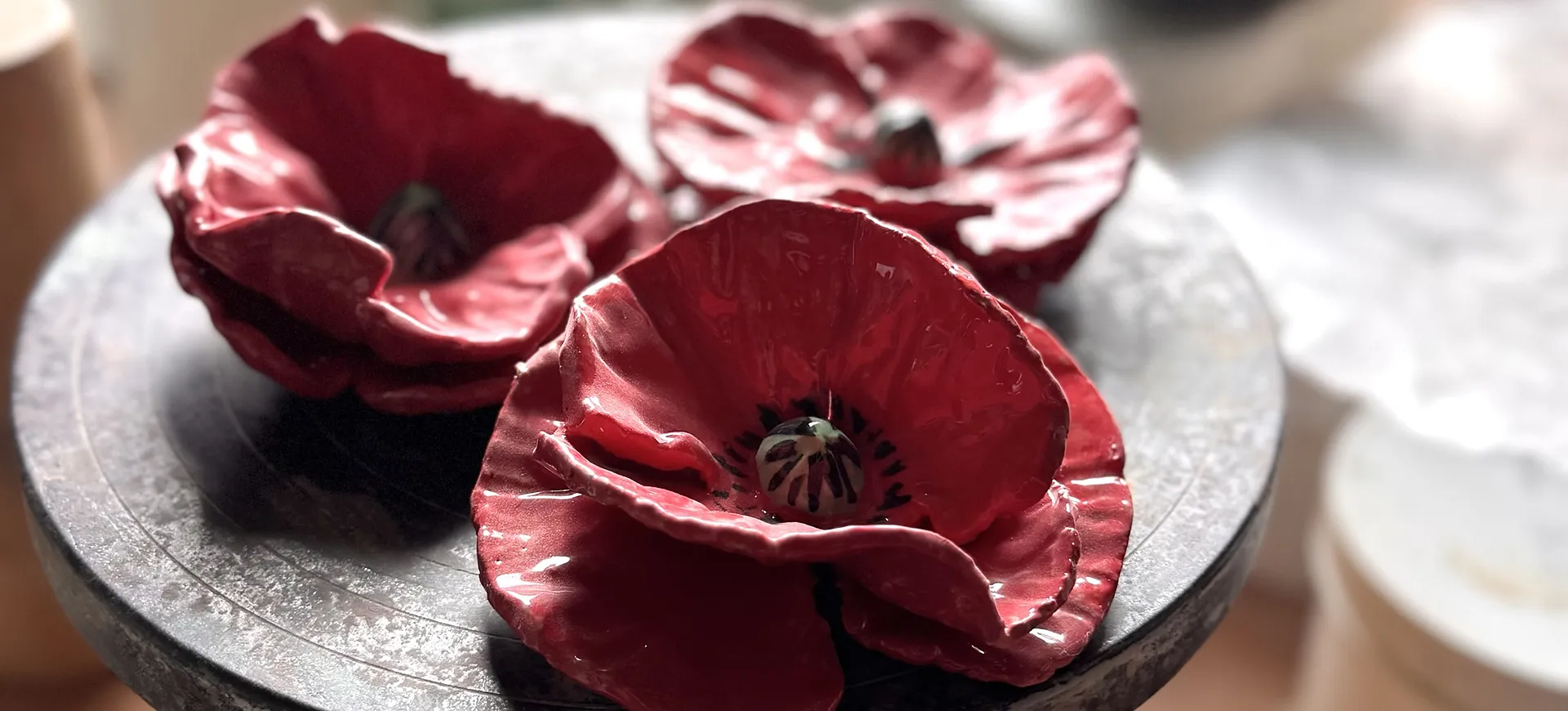 Drei rote Mohnblüten aus Keramik auf dem Drehteller im Atelier